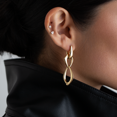 Gold earrings worn by a person with a black garment
