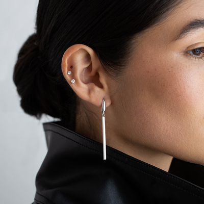 Close-up of a person wearing a silver earring with a blurred background