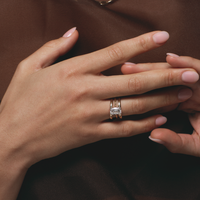 Close-up of a hand wearing a diamond ring on a dark background