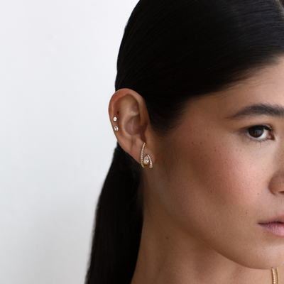 Close-up of a woman wearing a diamond earring with a plain background