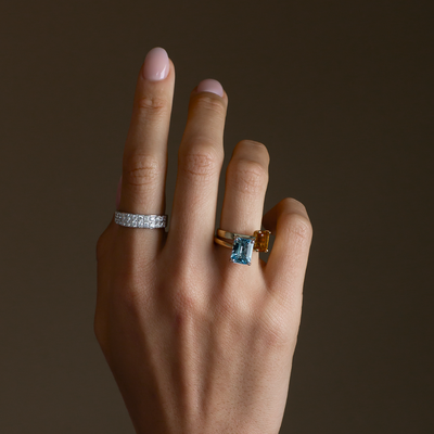 Hand wearing two rings with a dark background