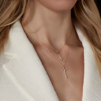Close-up of a person wearing a delicate gold necklace with a cross pendant.