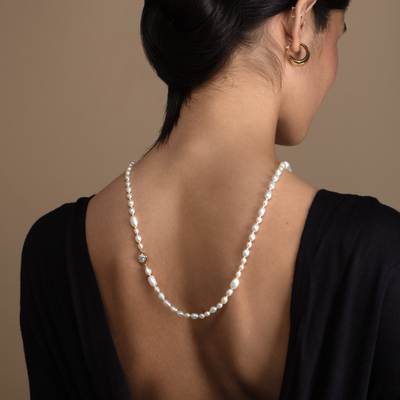 Woman wearing a pearl necklace with a neutral background