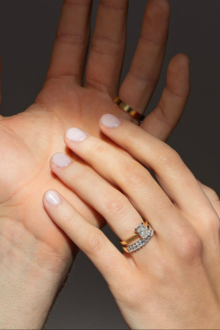 Two hands with rings on a dark background