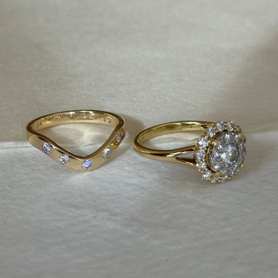 Two gold rings with diamond accents on a light background