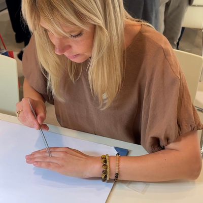 Woman in a brown shirt using a tool on a white surface with blurred background