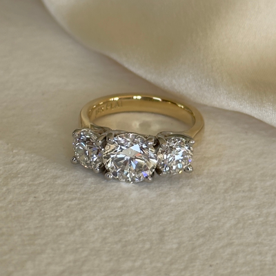 Gold ring with three diamonds on a beige fabric background
