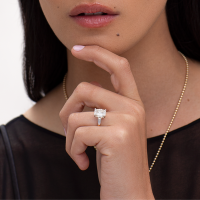 Close-up of a woman's hand wearing a diamond ring with a blurred background