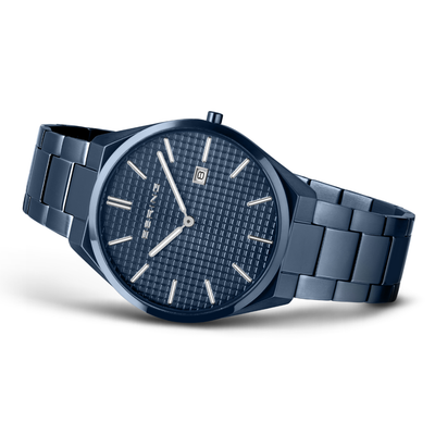 A men's analog watch with a dark blue metal bracelet and matching blue textured dial, featuring silver-tone hour markers and hands, and a date window at the 3 o'clock position.