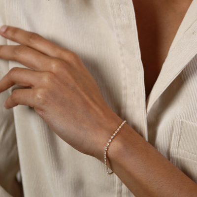 Close-up of a hand wearing a delicate bracelet on a neutral background