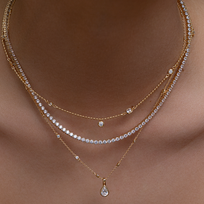 Layered gold necklaces with diamond accents on a skin background