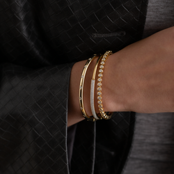 Close-up of a wrist wearing multiple gold bracelets against a dark background