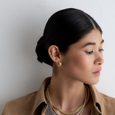 Woman with styled hair and jewelry against a plain background