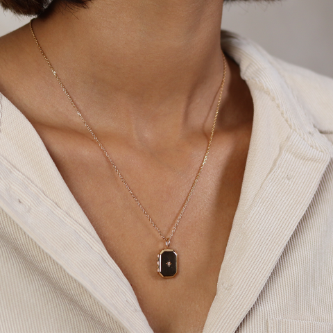 Necklace with a pendant worn by a person in a light-colored outfit