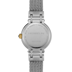 The back of a Herbelin watch with a silver stainless steel case and a textured gray mesh strap, featuring a small gold crown accent.