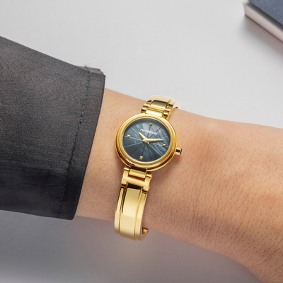 Gold wristwatch on a wrist with a blurred background