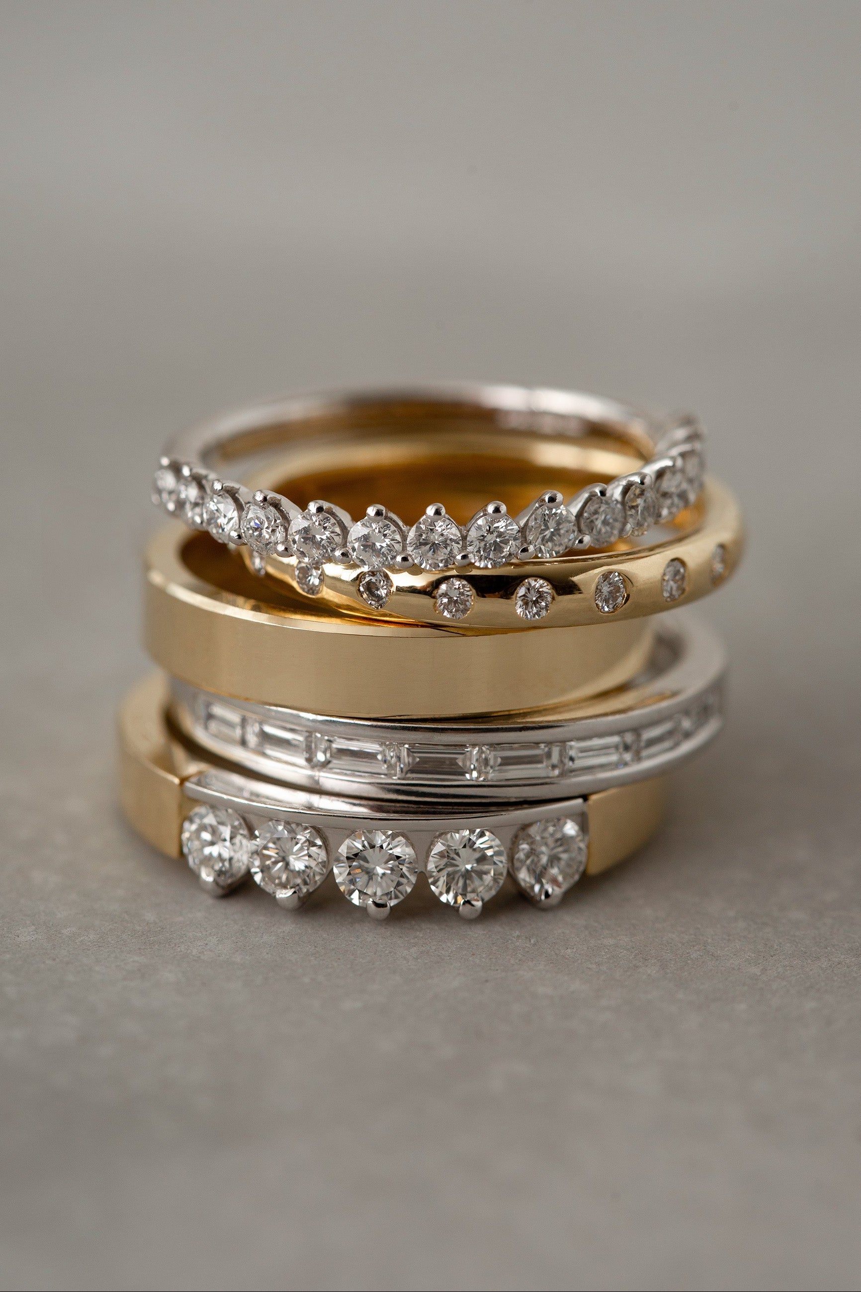 Three diamond-studded rings stacked on a gray surface