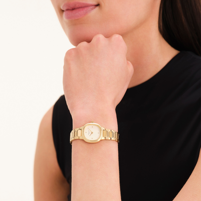 Gold watch on a wrist with a plain background