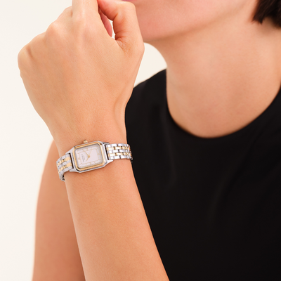 Silver watch on a wrist with a neutral background