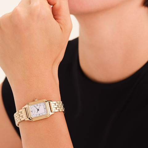 Gold wristwatch on a person's wrist with a blurred background