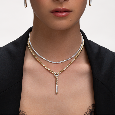 Close-up of a person wearing multiple necklaces with a neutral background