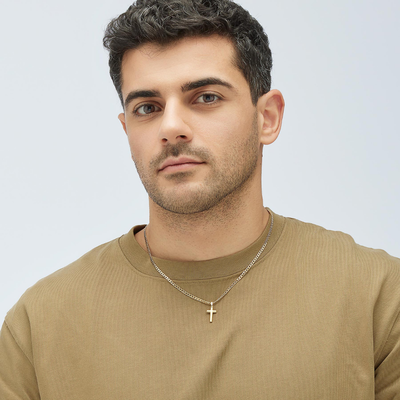 Man wearing a gold necklace with a cross pendant on a light gray background