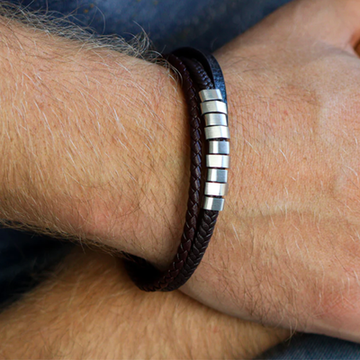 Close-up of a wrist wearing a brown leather bracelet with metal accents.