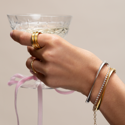 Model wearing bracelet stack carrying cocktail glass