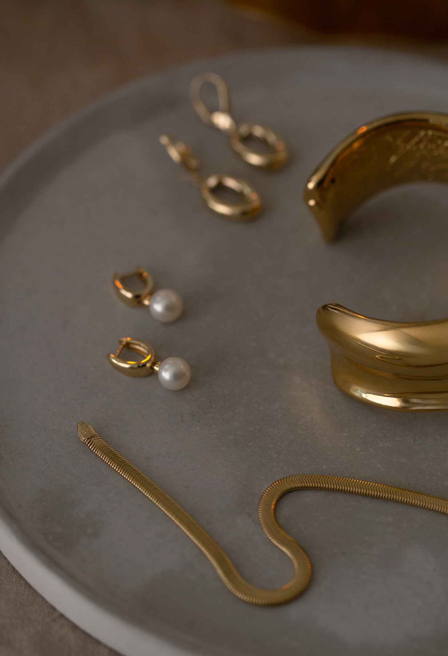 Gold and pearl jewelry on a gray surface