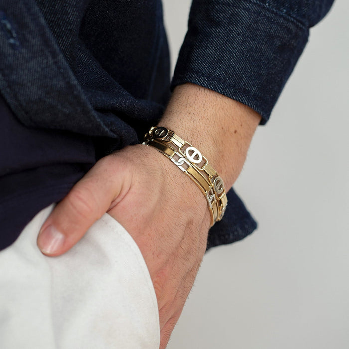 Gold bracelet on a wrist with a neutral background
