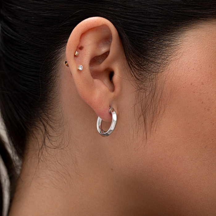 Close-up of an ear with earrings against a neutral background